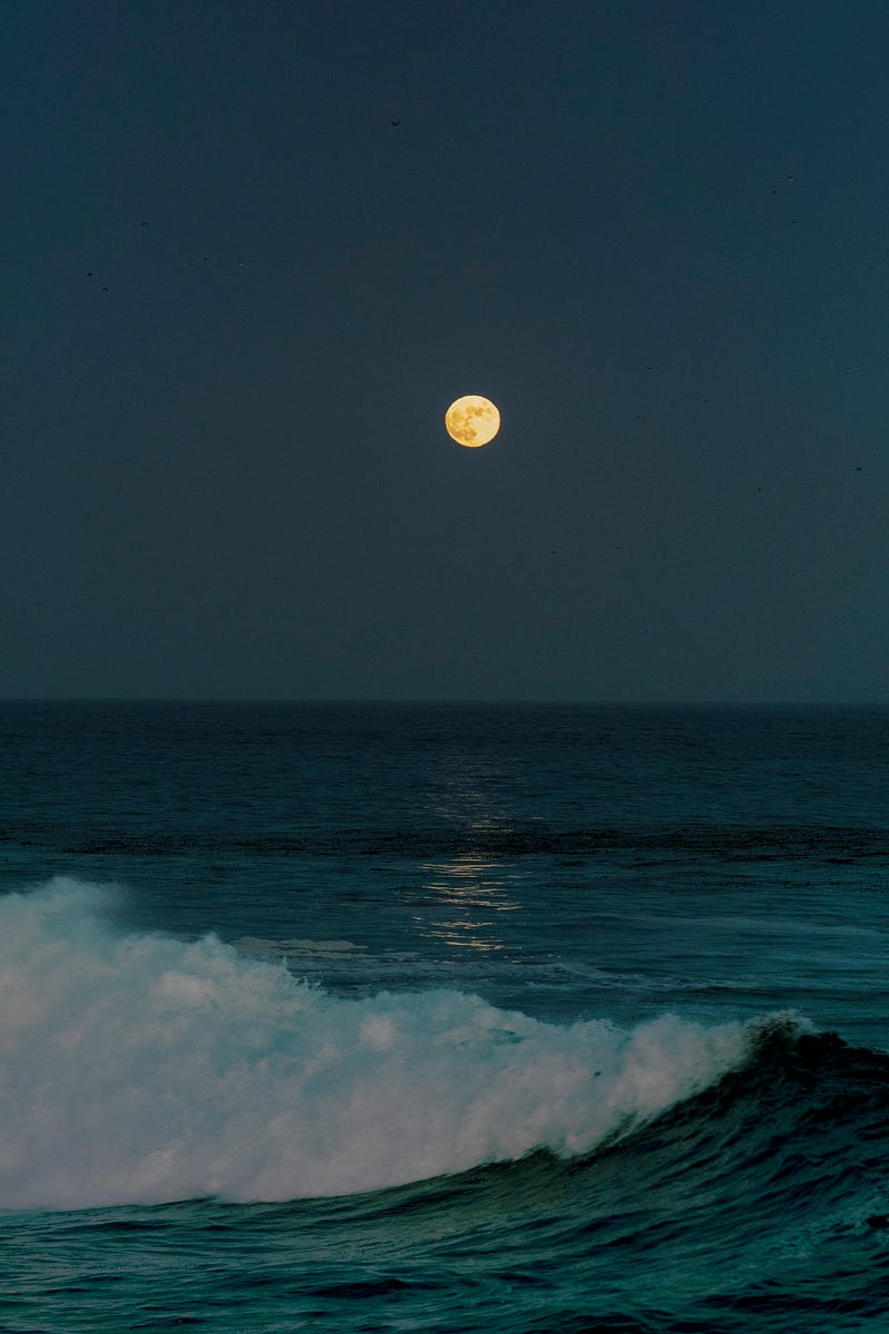 Full moon glowing over dark ocean waves at night, with moonlight reflecting across the water.