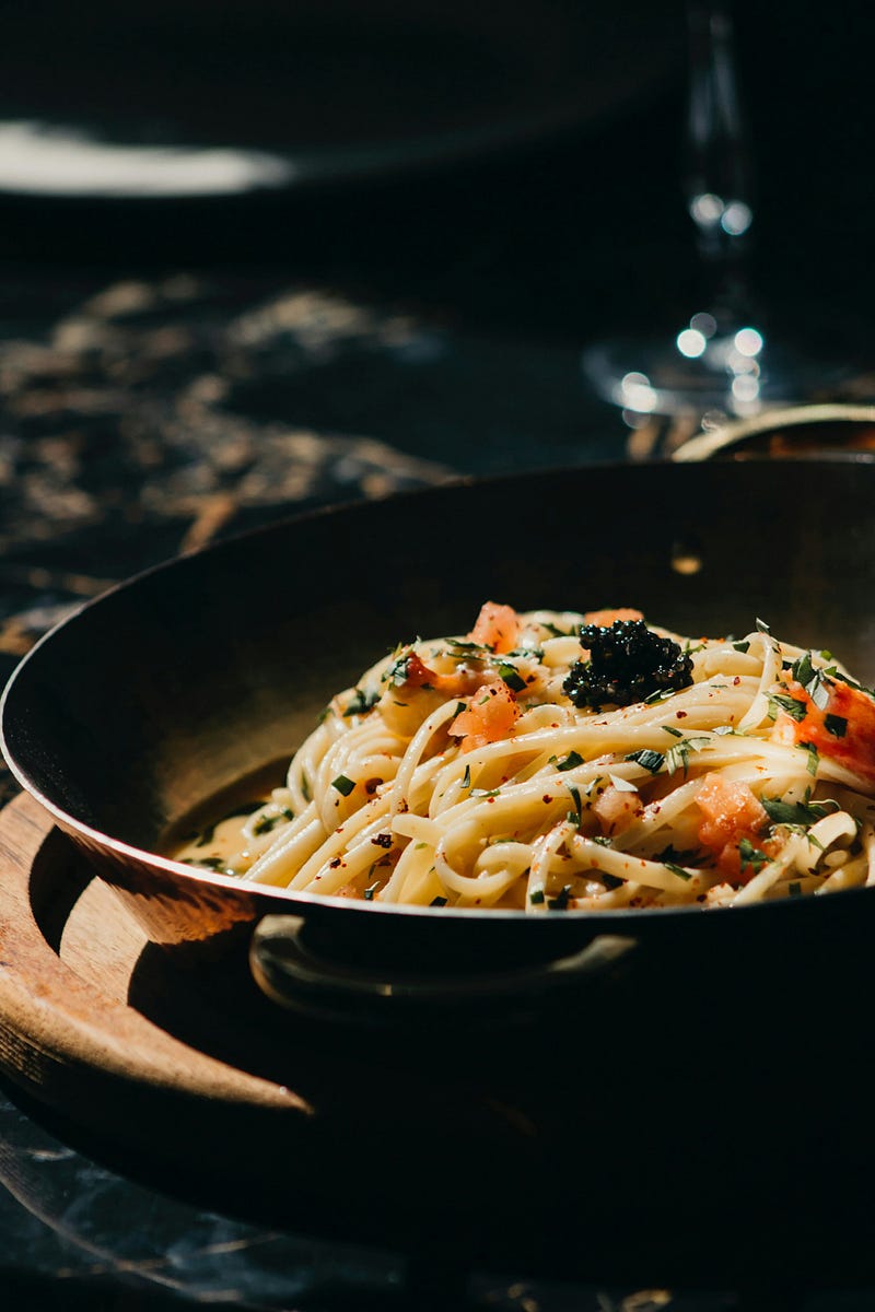 Close up of pan with long noodle pasta and toppings.