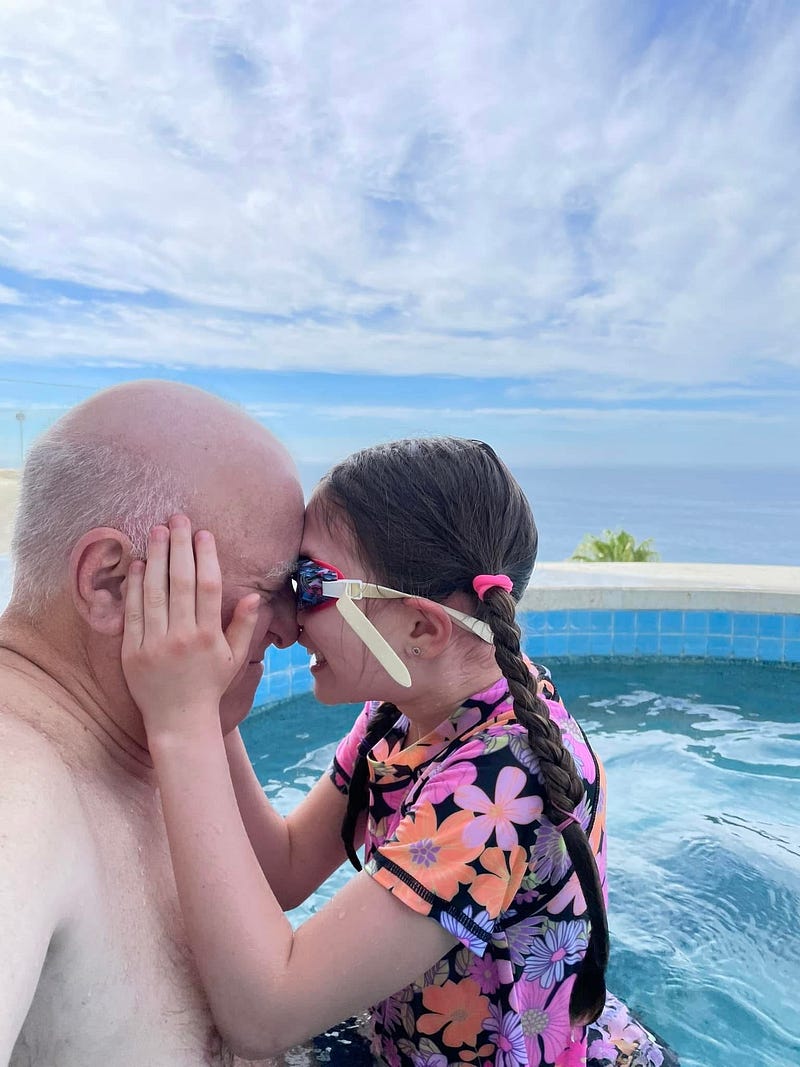 A grandfather and his niece share a quiet, playful moment of connection in the water.